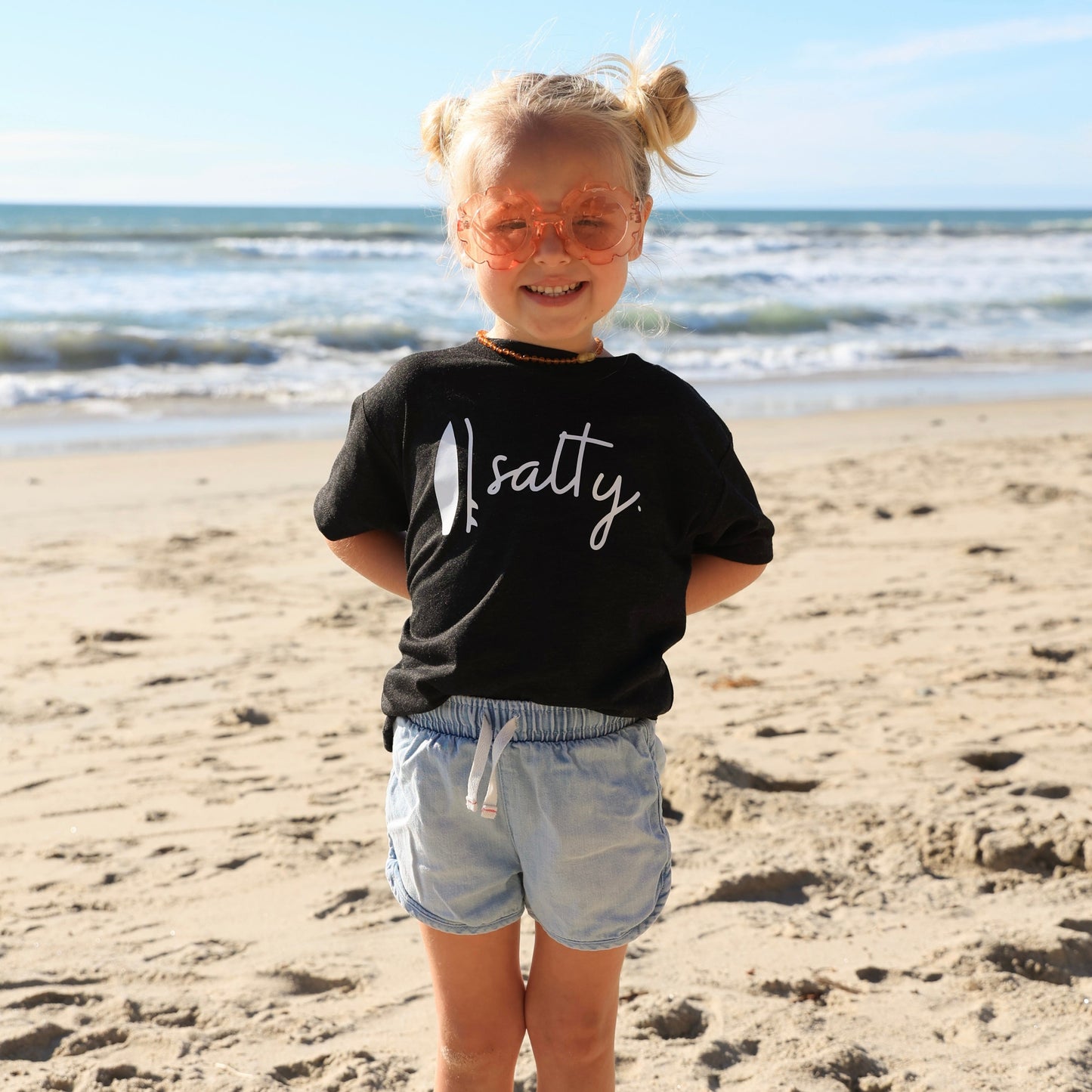 little girl wearing a black Salty Surf T-Shirt on the beach