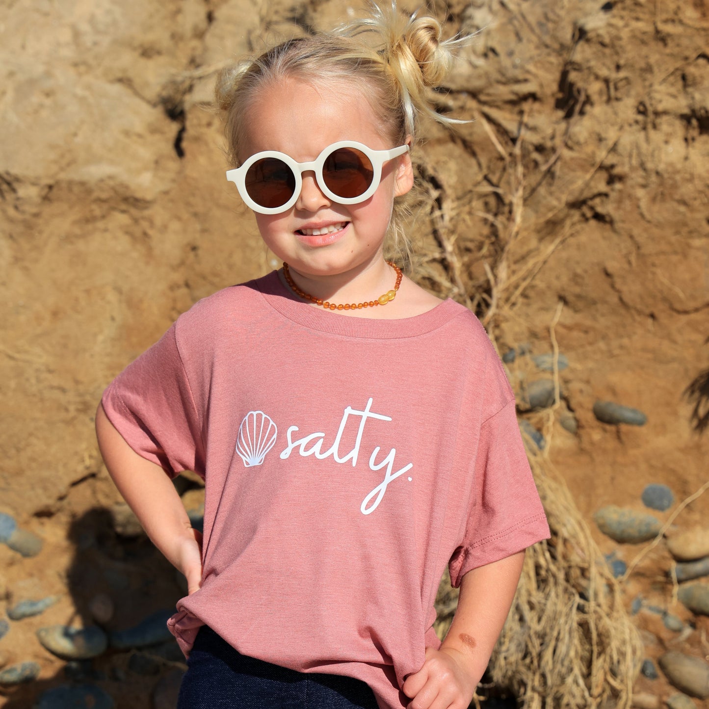 Little girl wearing a pink Salty Shell T-Shirt on the beach